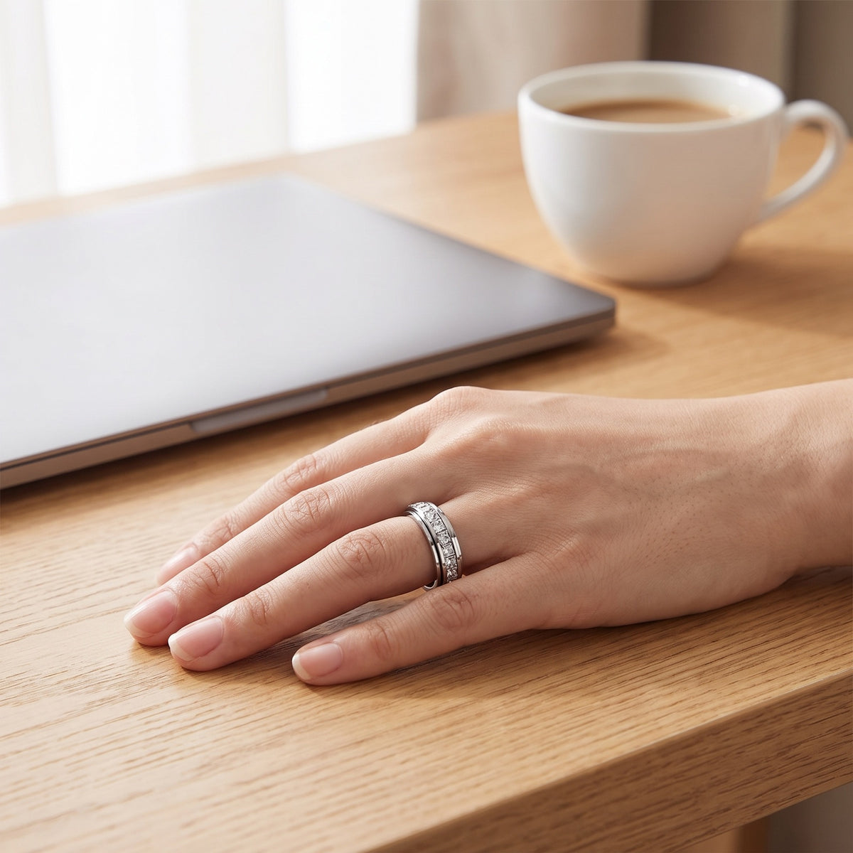 Calm Spinner Ring – worn on a hand resting on a desk beside a laptop and coffee