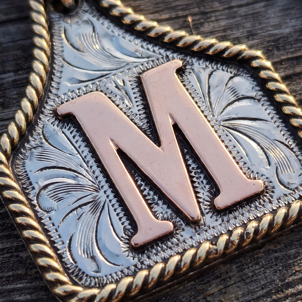 Cow Tag Initial Necklace & Keychain – macro of the hand engraving, twisted gold rope border and raised copper letter M