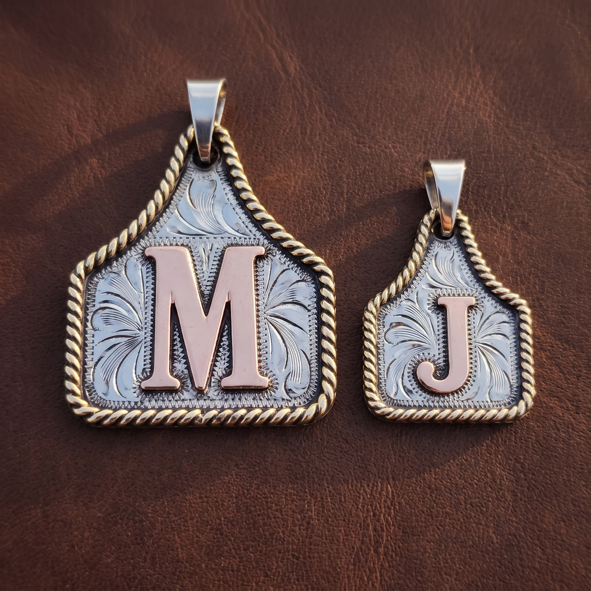 Cow Tag Initial Necklace & Keychain – Large (letter M) and Small (letter J) tags side by side on dark leather