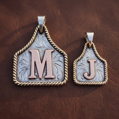 Initial Cow Tag pendants, a Large M and a Small J, on dark leather